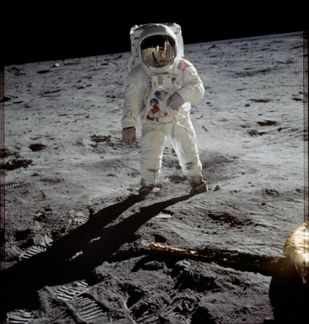 Astronaut Buzz Aldrin standing on the surface of the moon during the Apollo 11 moonwalk. The reflection in the visor of his spacesuit shows the photographer astronaut Neil Armstrong and the earth. 